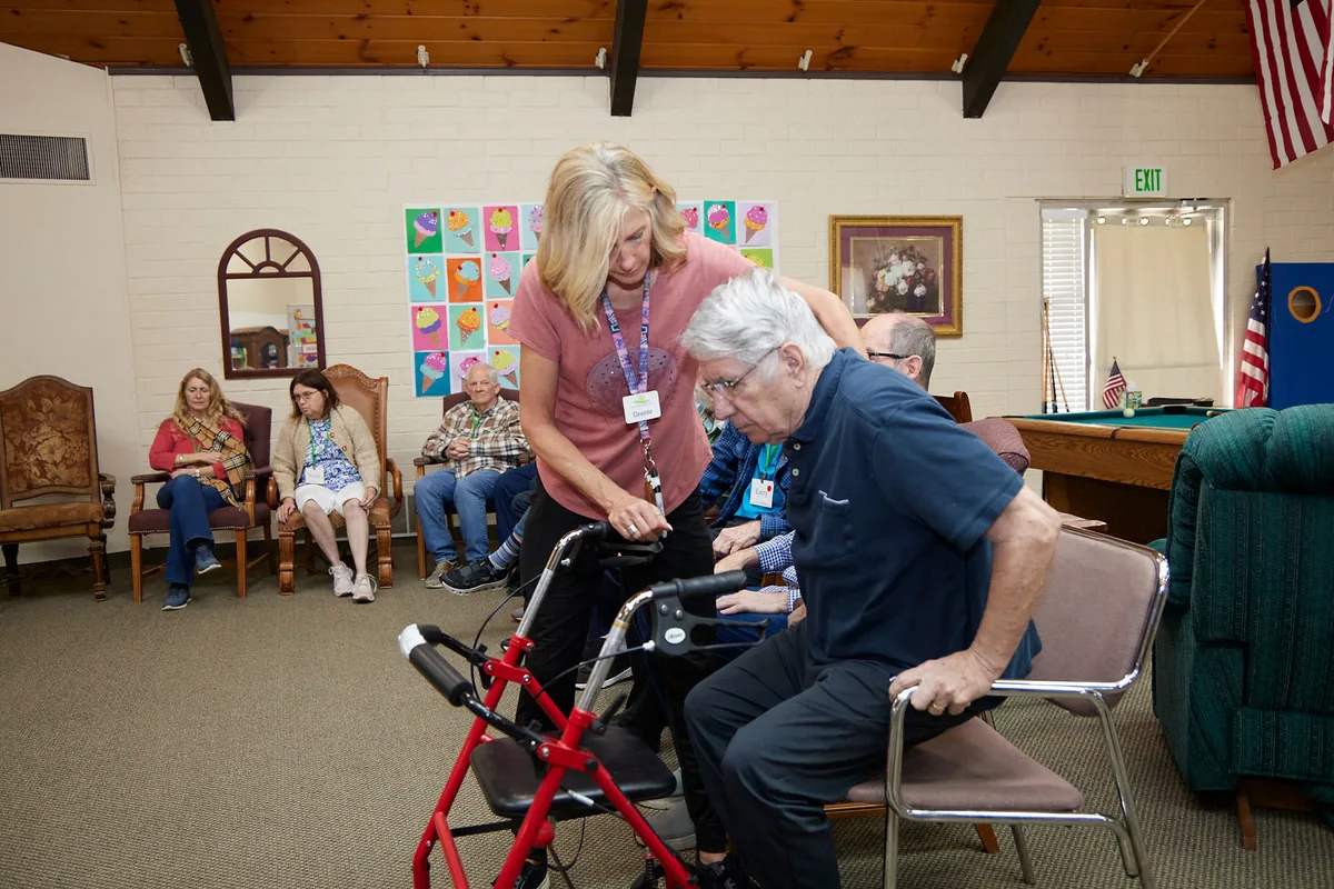 An Aspen aide helps a participant using a walker at Aspen Senior Day Center