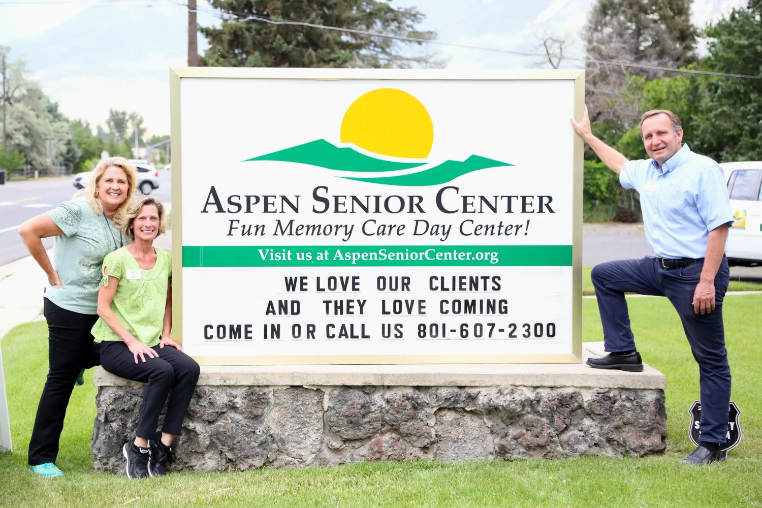 Pam Hicks, Julie Smith, and Gary Staples smiling beside the Aspen Senior Center sign on Canyon Road