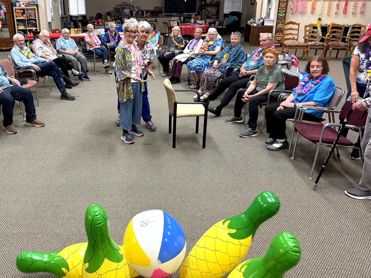 Participants in leis gathered in a circle for inflatable bowling at Aspen Senior Day Center